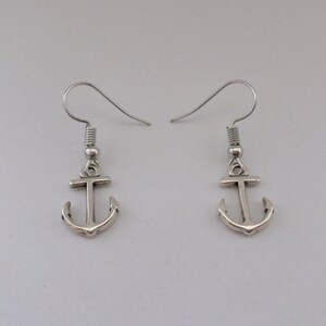 Könnte beinhalten: Ein Paar silberne Ankerohrringe mit einem schlichten Design. Die Ohrringe sind aus Metall und haben einen Hakenverschluss.