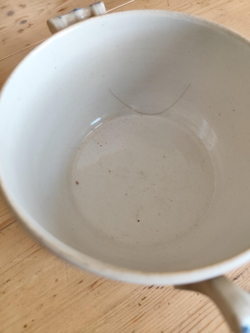 Op de afbeelding: Witte keramische serveerschaal met een blauw-wit bloemenmotief. De schaal heeft aan elke kant een handvat en een deksel.