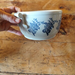 Op de afbeelding: Witte keramische kom met een blauw bloemenpatroon en twee handvatten.