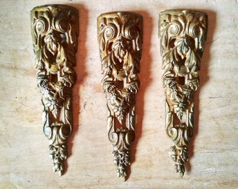 May include: Three ornate gold-colored metal decorative pieces with intricate floral and scroll designs.