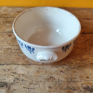 K&ouml;nnte beinhalten: Eine wei&szlig;e Keramiksch&uuml;ssel mit einem blauen und wei&szlig;en Blumenmuster. Die Sch&uuml;ssel hat einen einzigen Griff und ist perfekt zum Servieren von Suppe oder anderen Gerichten.