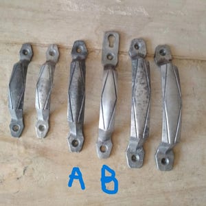 May include: Seven silver-toned metal drawer pulls with a diamond-shaped design. The pulls have a slightly distressed finish.