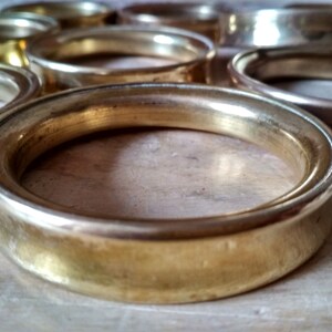 May include: A set of gold-toned metal rings, each with a smooth, rounded edge. The rings are stacked on top of each other, creating a decorative and elegant display.