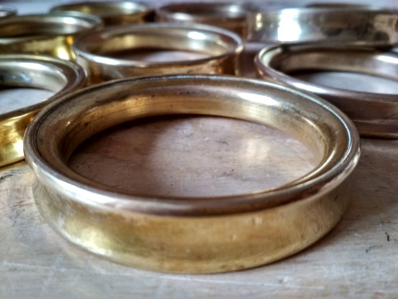 May include: A set of gold-toned metal rings, each with a smooth, rounded edge. The rings are stacked on top of each other, creating a decorative and elegant display.