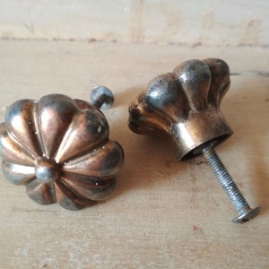 Peut inclure: Deux boutons de porte en métal de style antique avec un motif floral. Les boutons sont une combinaison de tons cuivre et argent. Chaque bouton est doté d'une vis pour la fixation à une porte de placard.