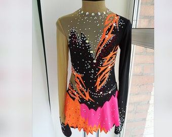 May include: A black leotard with long sleeves and a pink and orange skirt. The leotard is decorated with rhinestones and a geometric design.