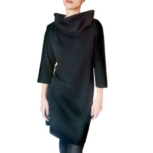 Könnte beinhalten: Ein schwarzes Kleid mit Rollkragen und langen Ärmeln. Das Kleid ist aus einem weichen, bequemen Stoff und hat eine lockere Passform.