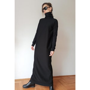 May include: A long, black dress with a turtleneck and long sleeves. The dress is floor-length and worn with black ankle boots. The person in the image is wearing sunglasses.