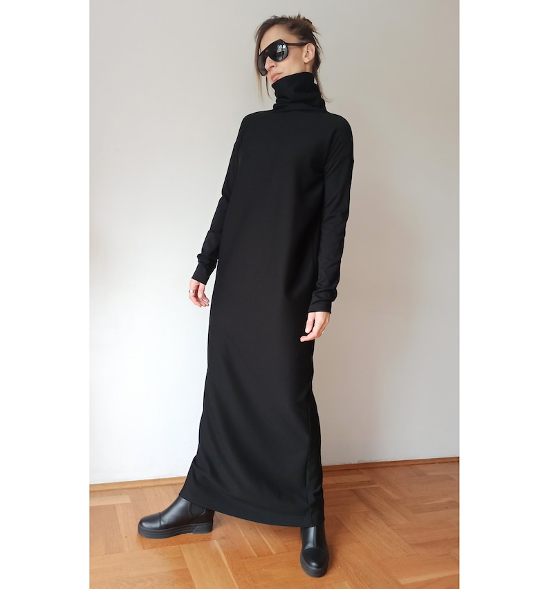 May include: A long, black dress with a turtleneck and long sleeves. The dress is floor-length and worn with black ankle boots. The person in the image is wearing sunglasses.