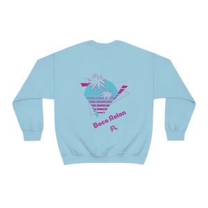 May include: Light blue sweatshirt with a retro-style graphic of palm trees and a sunset, with the text "Boca Raton FL" in pink.