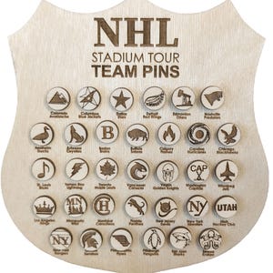 May include: Wooden shield-shaped display board featuring NHL Stadium Tour Team Pins. The board has a light wood finish and holds 30 circular pins, each with a team logo. The text "NHL STADIUM TOUR TEAM PINS" is at the top.