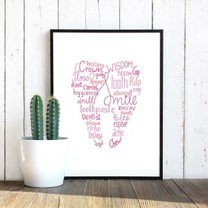 May include: A framed print with a pink and white tooth-shaped word cloud. The word cloud includes words related to dental health, such as "wisdom teeth", "tooth pulp", "smile", "dentist", "plaque", "decay", and "ache".