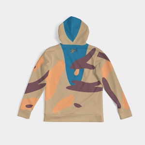 Puede incluir: Sudadera con capucha color beige con capucha y panel trasero azules, con formas abstractas naranjas y marrones. La parte trasera de la capucha tiene un peque&ntilde;o logotipo. Mangas largas con patrones abstractos a juego. Prenda casual y c&oacute;moda.