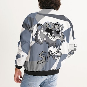 May include: A white and gray bomber jacket with a cartoon bear graphic on the back. The bear has a stitched-up mouth and a bandage on its eye. The text "STAG" is stitched on the jacket below the bear.
