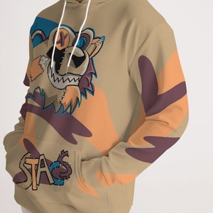 Puede incluir: Sudadera con capucha de color canela con un dise&ntilde;o de oso de dibujos animados. El oso tiene una cara cosida y una sonrisa. La sudadera con capucha tiene un bolsillo de canguro y la palabra "STA" cosida en el bolsillo. Formas abstractas naranjas y moradas decoran las mangas.