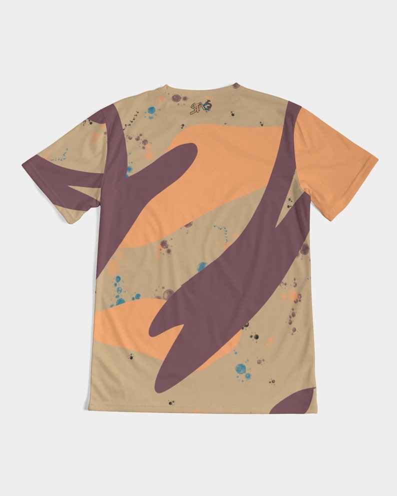 Op de afbeelding: T-shirt met korte mouwen met een beige achtergrond en abstracte vormen in oranje en donkerpaars. Het shirt heeft een ronde hals en een klein logo bij de halslijn. Blauwe en bruine verfspatten zijn over het shirt verspreid.