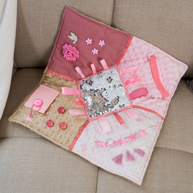 On the front part of the mat there are different fidget elements: Colorful Tassel pendants, felt decorations, Different textures of ribbons and fabrics