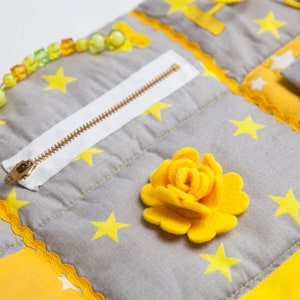 Sensory mat details in different texture for tactile stimulation: Zipper, plastic buckle, different button and ribbons, felt decoration, pocket, ties, snap button, and other sensory texture