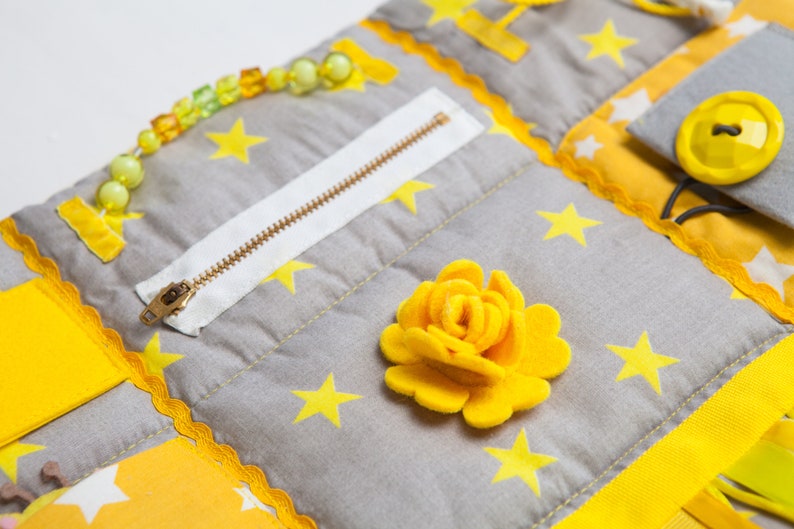 Sensory mat details in different texture for tactile stimulation: Zipper, plastic buckle, different button and ribbons, felt decoration, pocket, ties, snap button, and other sensory texture