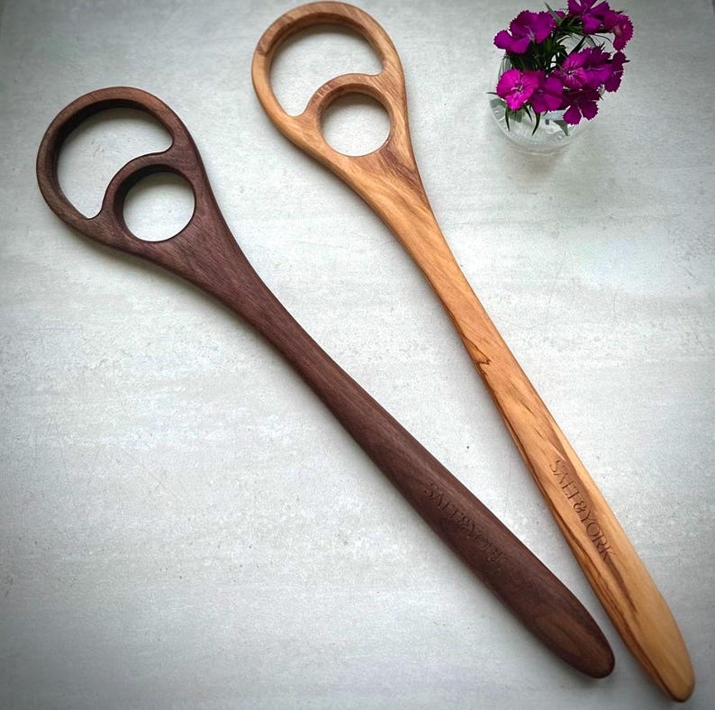 Pu&ograve; includere: Due cucchiai di legno con design unici del manico. Uno &egrave; marrone scuro, l'altro &egrave; marrone chiaro. Entrambi hanno un'apertura circolare e un foro pi&ugrave; piccolo nel manico. Il cucchiaio marrone chiaro ha inciso "SALT & YORK".