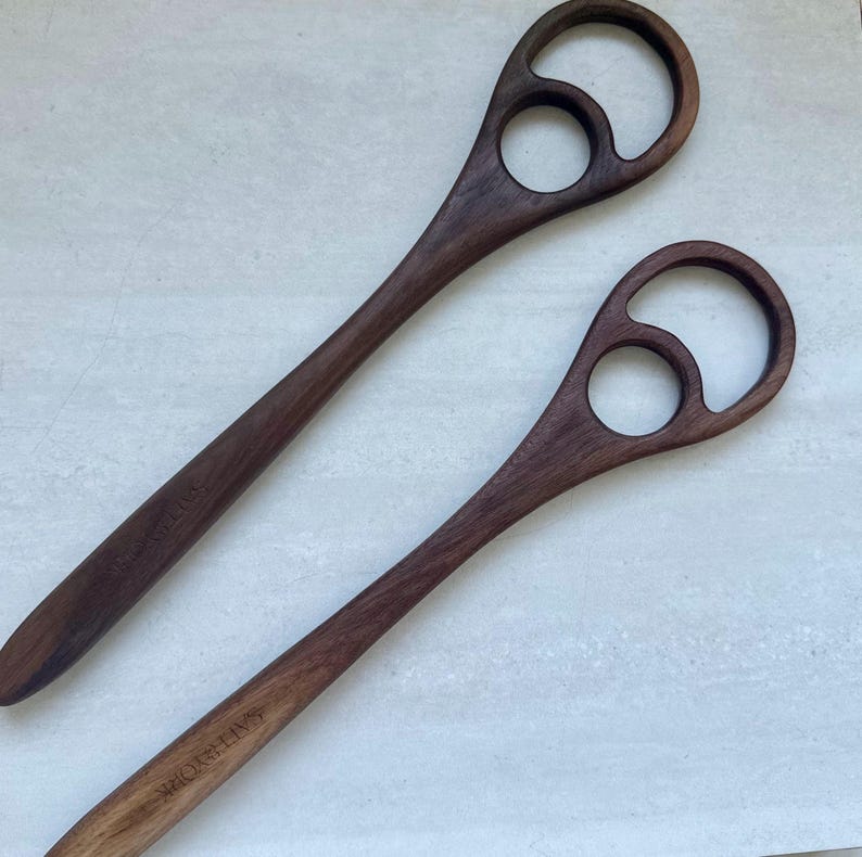 Pu&ograve; includere: Due utensili da portata per insalata in legno marrone scuro. Ogni utensile ha un lungo manico e un design unico nella parte superiore con due ritagli circolari. Il testo "SAYRE YORK" &egrave; inciso sul manico di ciascuno.