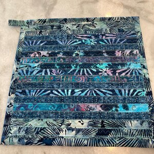 May include: A blue and white quilted hot pad with a floral pattern. The hot pad has a loop for hanging.