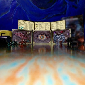 Könnte beinhalten: Ein Brettspiel mit blauem Hintergrund und einem Satz Karten mit Illustrationen von Augen, Zähnen und einer geflügelten Kreatur. Die Karten haben Titel wie "Dein Zug", "Wichtige Informationen" und "Bedingungen".