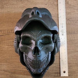 Op de afbeelding: Een zwart 3D-geprint schedelbeeld met een helm-achtig ontwerp. De schedel heeft een gedetailleerd, getextureerd oppervlak en een dreigende uitdrukking.