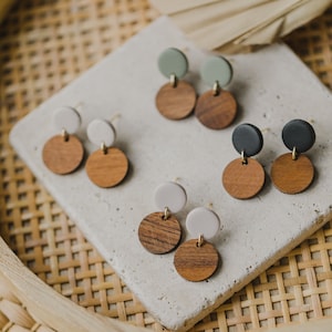 May include: A set of six wooden and colored clay earrings. The earrings are in three different color combinations: green and brown, white and brown, and black and brown.