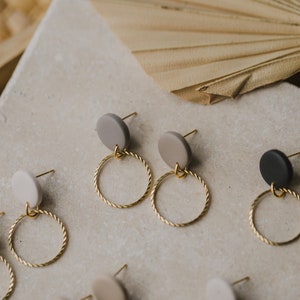 May include: A set of earrings with gold hoops and round clay charms in black, white, and gray.