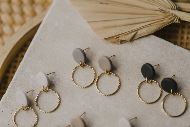 May include: A set of earrings with gold hoops and round clay charms in black, white, and gray.