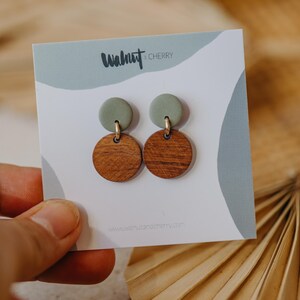 May include: A pair of earrings with a green clay top and a brown wood bottom. The earrings are on a white card with the text "Walnut & Cherry" and a website address.