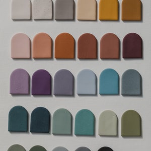 May include: A collection of 30 small, arched ceramic tiles in various colors, including white, gray, brown, purple, blue, green, and black.
