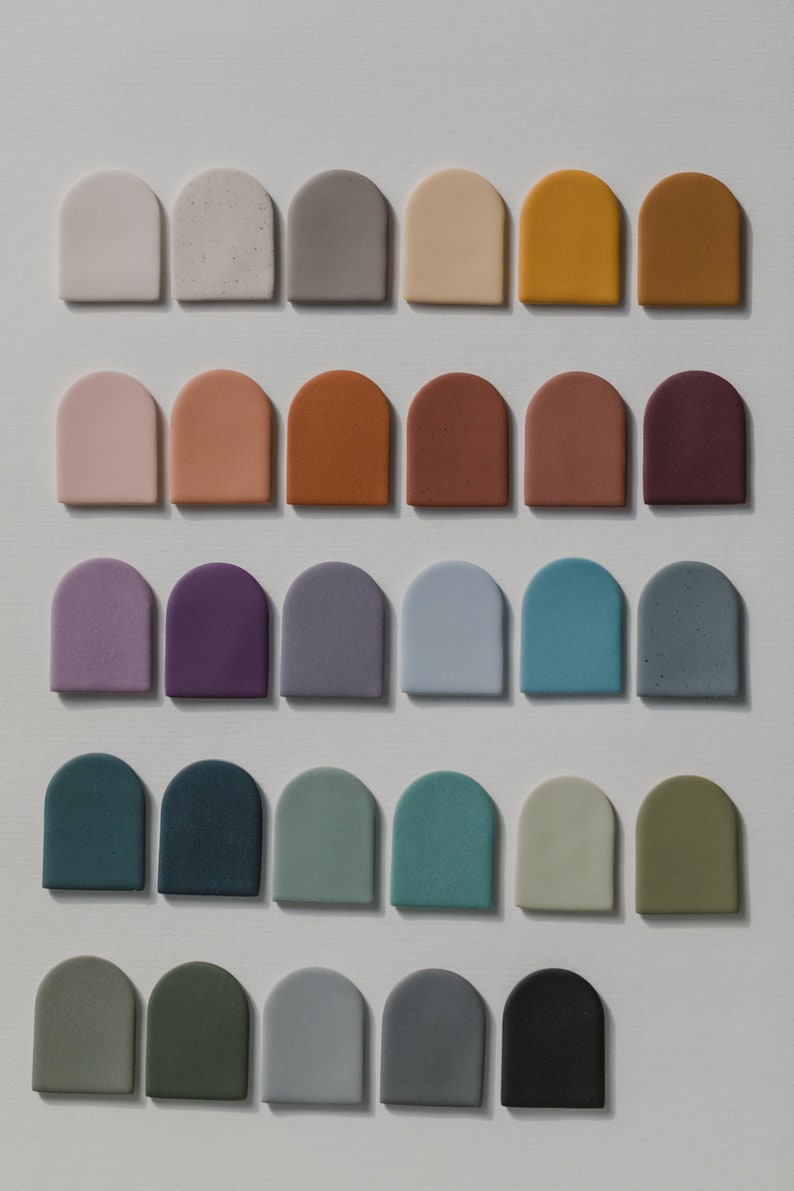 May include: A collection of 30 small, arched ceramic tiles in various colors, including white, gray, brown, purple, blue, green, and black.