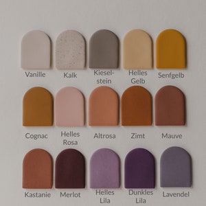May include: A color chart with 15 different paint colors in a semi-circle shape. The colors are named in German: Vanille, Kalk, Kieselstein, Helles Gelb, Senfgelb, Cognac, Helles Rosa, Altrosa, Zimt, Mauve, Kastanie, Merlot, Helles Lila, Dunkles Lila, Lavendel.
