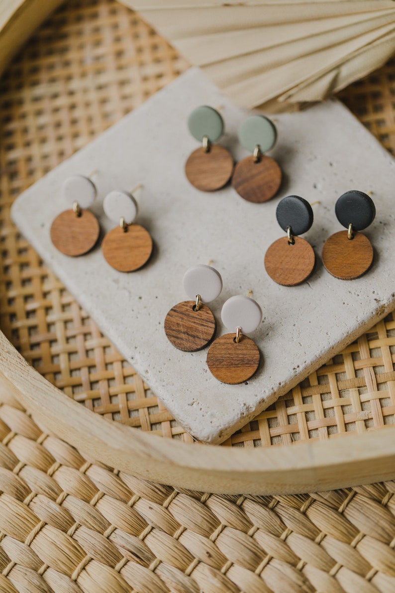 May include: A set of six wooden and colored clay earrings. The earrings are in three different color combinations: green and brown, white and brown, and black and brown.