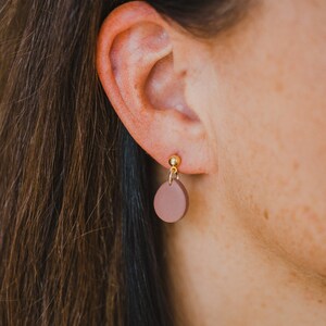 May include: A pair of brown clay earrings with gold posts. The earrings are shaped like small circles.