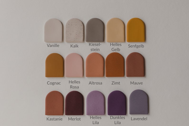 May include: A color chart with 15 different paint colors in a semi-circle shape. The colors are labeled with German names, including Vanille, Kalk, Kieselstein, Helles Gelb, Senfgelb, Cognac, Helles Rosa, Altrosa, Zimt, Mauve, Kastanie, Merlot, Helles Lila, Dunkles Lila, and Lavendel.