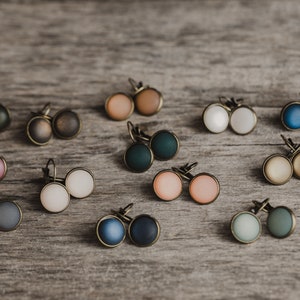 May include: Assortment of 12 pairs of earrings with round, colourful, and textured cabochons. The earrings have bronze-coloured metal settings.