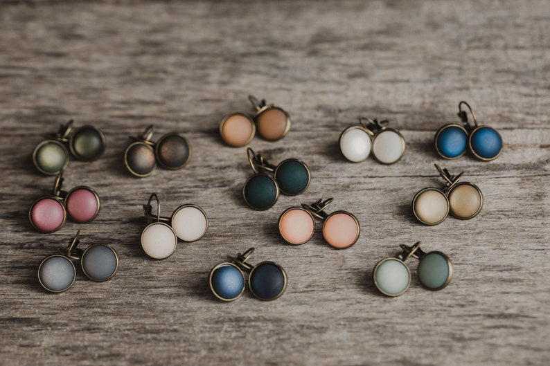 May include: Assortment of 12 pairs of earrings with round, colourful, and textured cabochons. The earrings have bronze-coloured metal settings.