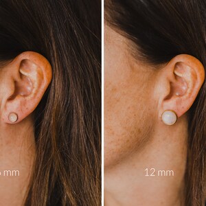 Op de afbeelding: Twee close-ups van een vrouwen oor met een ronde, witte edelsteen oorring. De linker afbeelding toont een 6 mm oorring en de rechter afbeelding toont een 12 mm oorring.