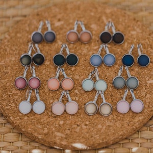 May include: A set of 12 pairs of earrings with different colored glass cabochons. The earrings are silver-toned and have a leverback closure.