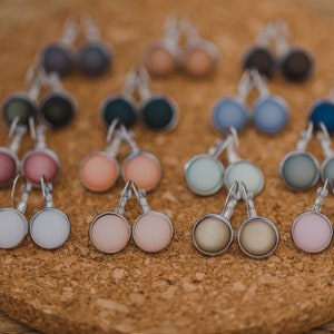 May include: A collection of 10 pairs of silver stud earrings with various colored glass cabochons. The colors include pink, peach, white, gray, blue, and green.