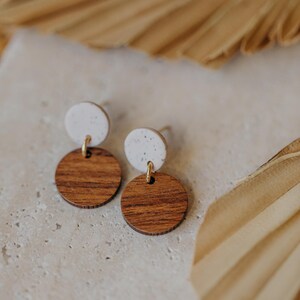May include: A pair of earrings with a white speckled round top and a brown wood round bottom.