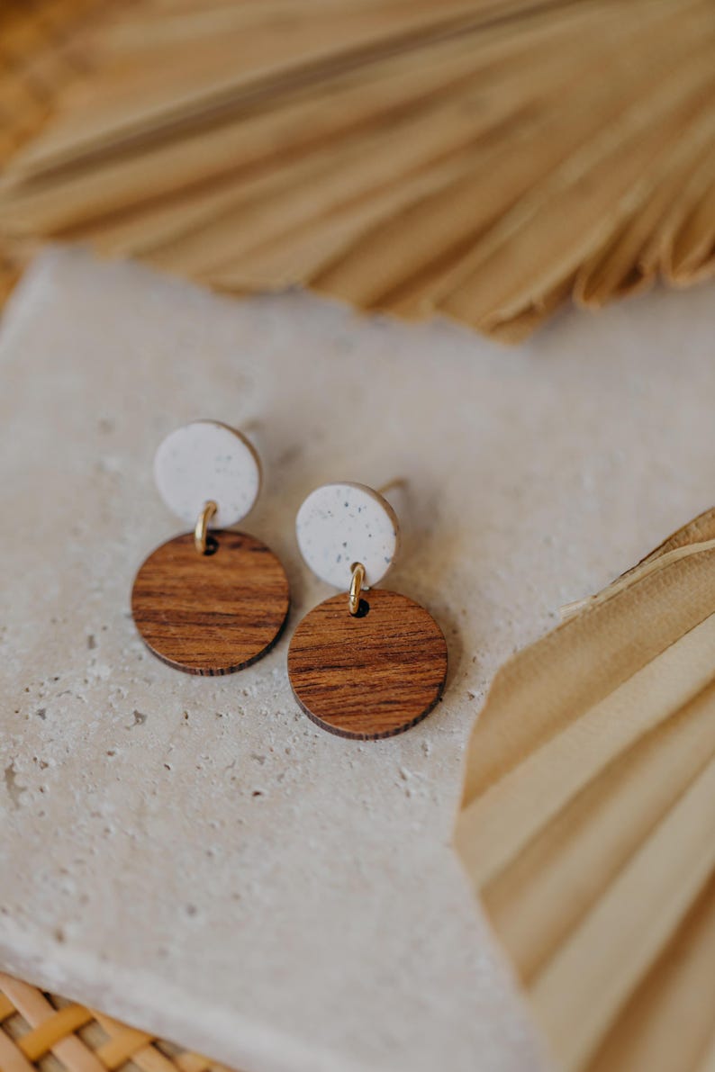 May include: A pair of earrings with a white speckled round top and a brown wood round bottom.