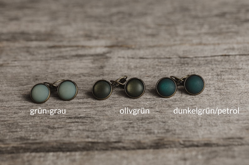 May include: Six pairs of earrings with different coloured glass cabochons. The colours are green-grey, olive green, and dark green/petrol.