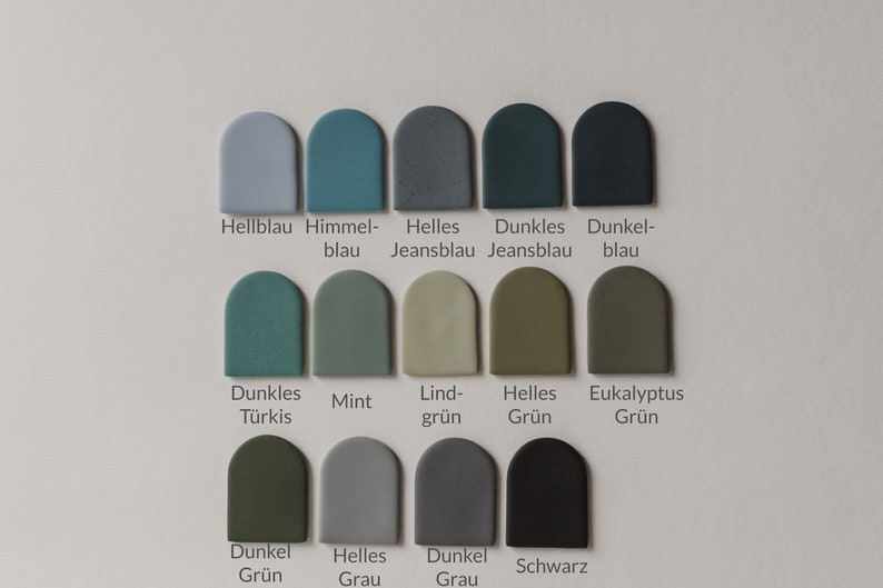 May include: Color chart with 12 paint swatches in various shades of blue, green, and gray. The swatches are arranged in three rows of four. Each swatch is labeled with a German word describing the color.