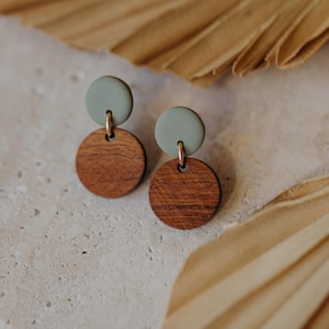 May include: A pair of wooden and green clay earrings. The earrings are round and have a simple design.