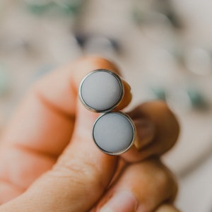Op de afbeelding: Een paar zilveren oorbel studs met ronde, ondoorzichtige witte stenen.