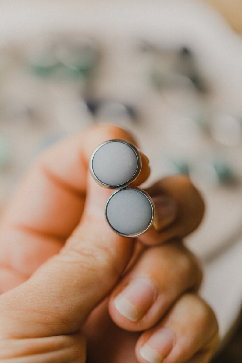 Op de afbeelding: Een paar zilveren oorbel studs met ronde, ondoorzichtige witte stenen.